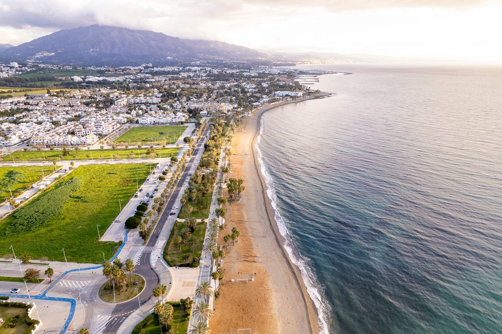 Aerial view of Benahavís, featuring a coastal road, sandy beach, and lush greenery.